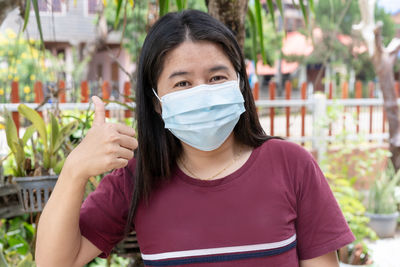Adult woman wearing medical face mask. pretty middle female showing finger thumb up for good sign.