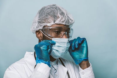 Doctor wearing mask standing against blue background