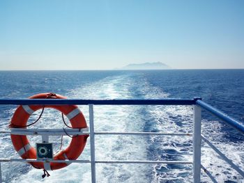 Boat sailing in sea against clear blue sky