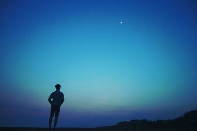 Rear view of man standing against clear blue sky