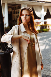 Fashionable young woman wearing overcoat in city