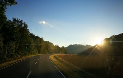 Road amidst trees against sky during sunset