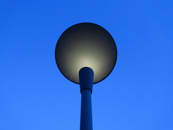 Low angle view of illuminated lamp against blue sky