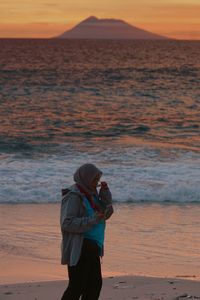 Woman standing at beach during sunset