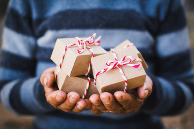 Midsection of man holding christmas presents while standing outdoors