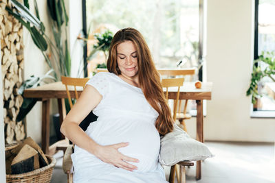 Cute young redhead freckled pregnant woman in white dress. concept of expectation of motherhood 