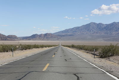 Empty road by mountains against sky