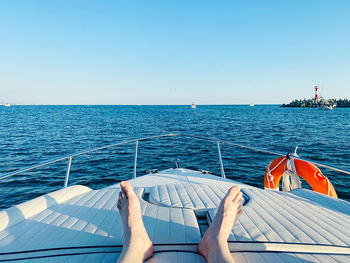 Low section of man relaxing on yacht against sky