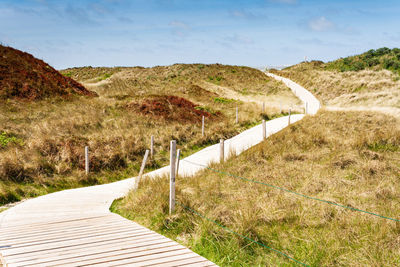 Footpath leading towards mountains against sky