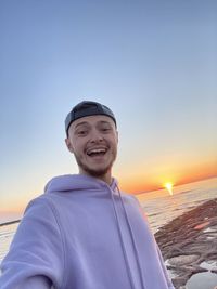 Portrait of smiling man in sea against sky during sunset