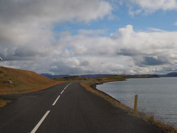 Empty road against cloudy sky