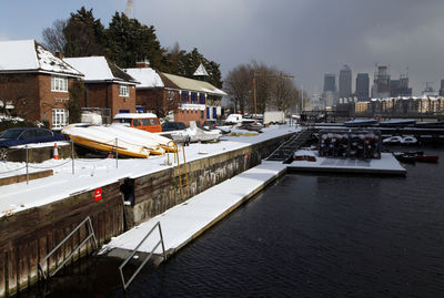 Boats moored on river in city against sky during winter