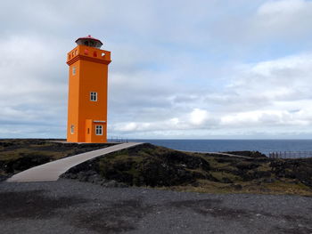 Lighthouse by sea against sky