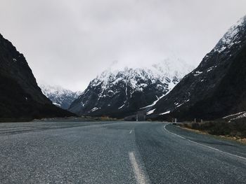 Road by mountains against sky