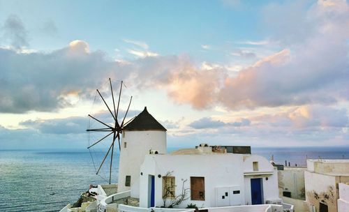 Traditional windmill by sea against sky