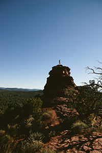 Mid distance view of man standing on mountain against clear blue sky
