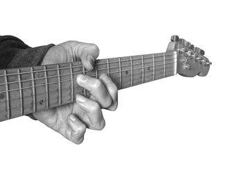 Close-up of hand playing guitar against white background