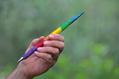 Close-up of hand holding colorful pen against plants