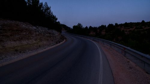 Road amidst trees against clear sky