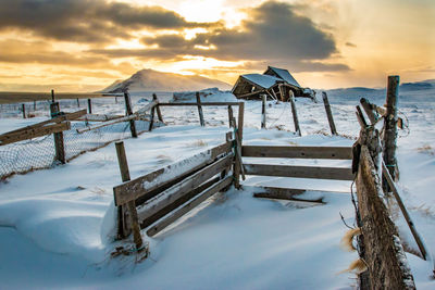 Scenic view of snow covered land against sky during sunset
