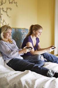 Two young women playing video game in bedroom