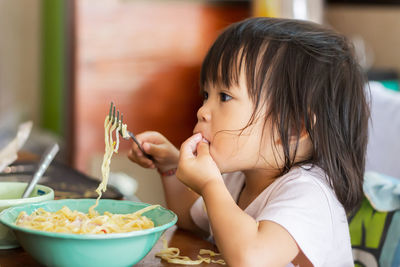 Cute baby girl eating noodles