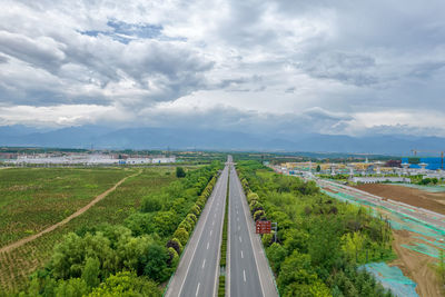 Road passing through city against sky