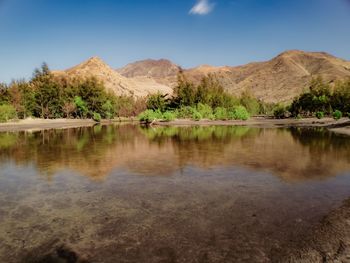 Scenic view of lake by mountain against sky