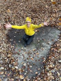High angle view of boy with yellow leaves during autumn