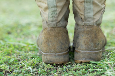 Low section of person wearing boots standing on field