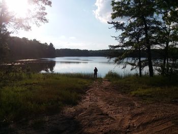 Man standing by lake against sky