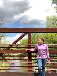 Full length of man standing on railing against sky