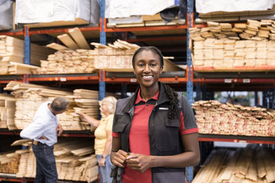 Portrait of smiling saleswoman standing in front of rack at hardware store