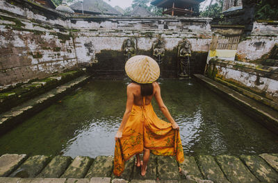 Rear view of woman with umbrella in canal