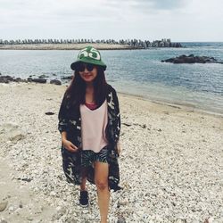 Portrait of smiling young woman standing on beach