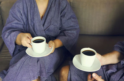 Midsection of man holding coffee cup