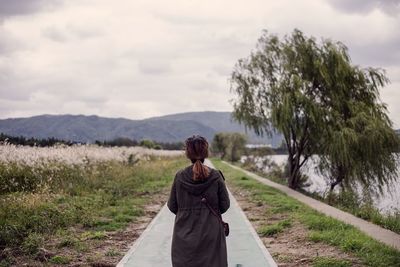 Rear view of woman walking on road against sky