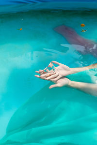 Cropped hand of woman holding pyramid crystal in swimming pool