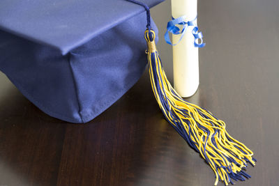 Close-up of mortarboard with certificate on table