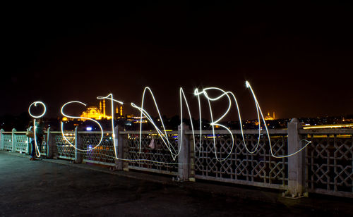 Light trails on bridge in city against clear sky at night