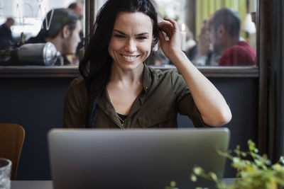 Happy creative businesswoman using laptop while sitting in office
