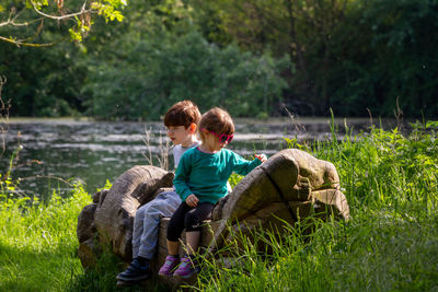 A cute redhead boy and girl with sunglasses sitting on a logon a sunny day