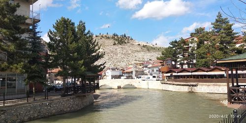 Canal amidst trees and buildings against sky