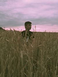 Teenage boy standing on field against sky