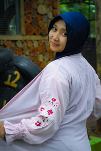 Portrait of young woman standing against wall