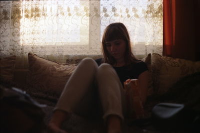 Young woman sitting on sofa at home