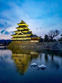 View of building by lake against sky