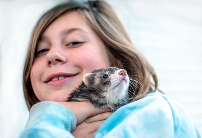 Young girl cuddles with her pet ferret
