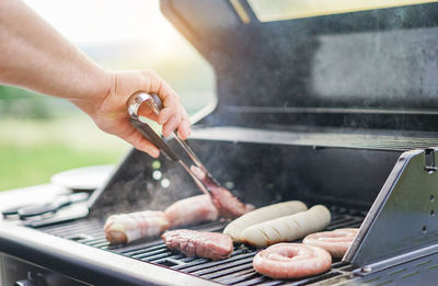 Cropped hand of man cooking meat on barbecue