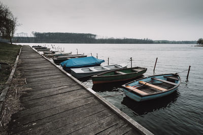 Boats moored by pier over lake